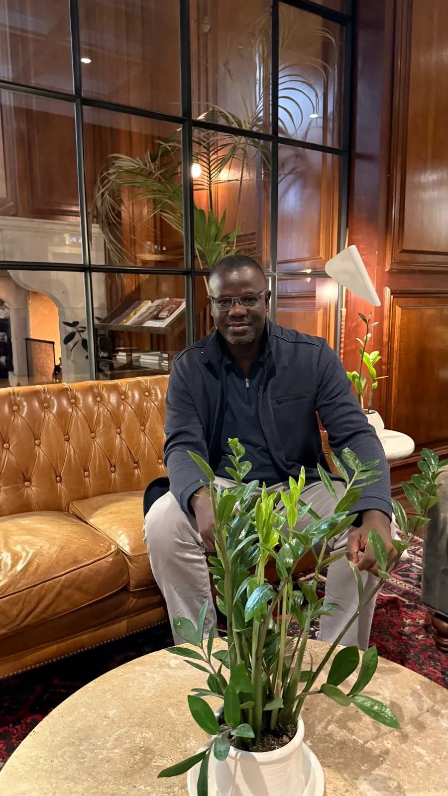 Tamba Sheku Lamin, seated indoors, smiling, in a dark jacket